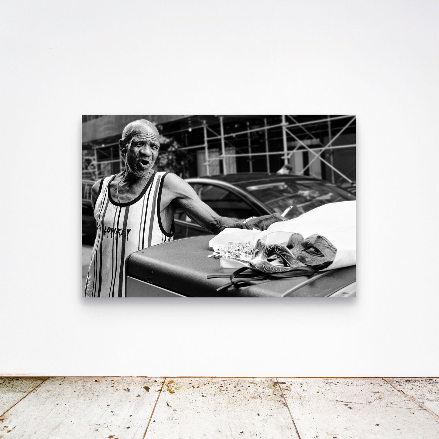 Chloe Albert's fine art print 'Mask Seller' shown unframed at 60 by 40 inches on a gallery wall above a concrete floor, displaying the large statement size in a room.