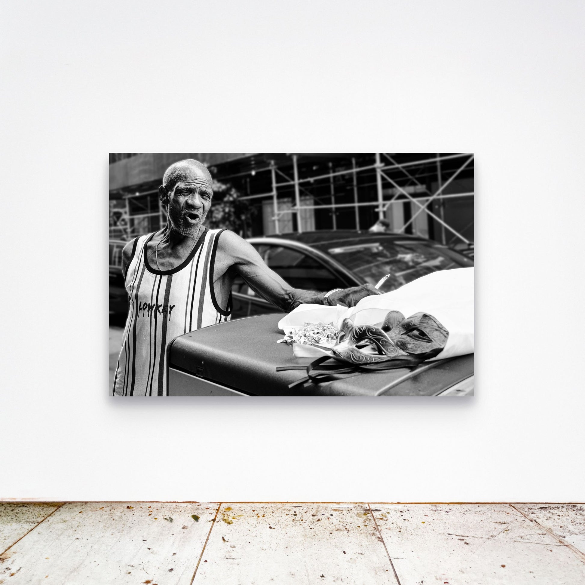 Chloe Albert's fine art print 'Mask Seller' shown unframed at 60 by 40 inches on a gallery wall above a concrete floor, displaying the large statement size in a room.