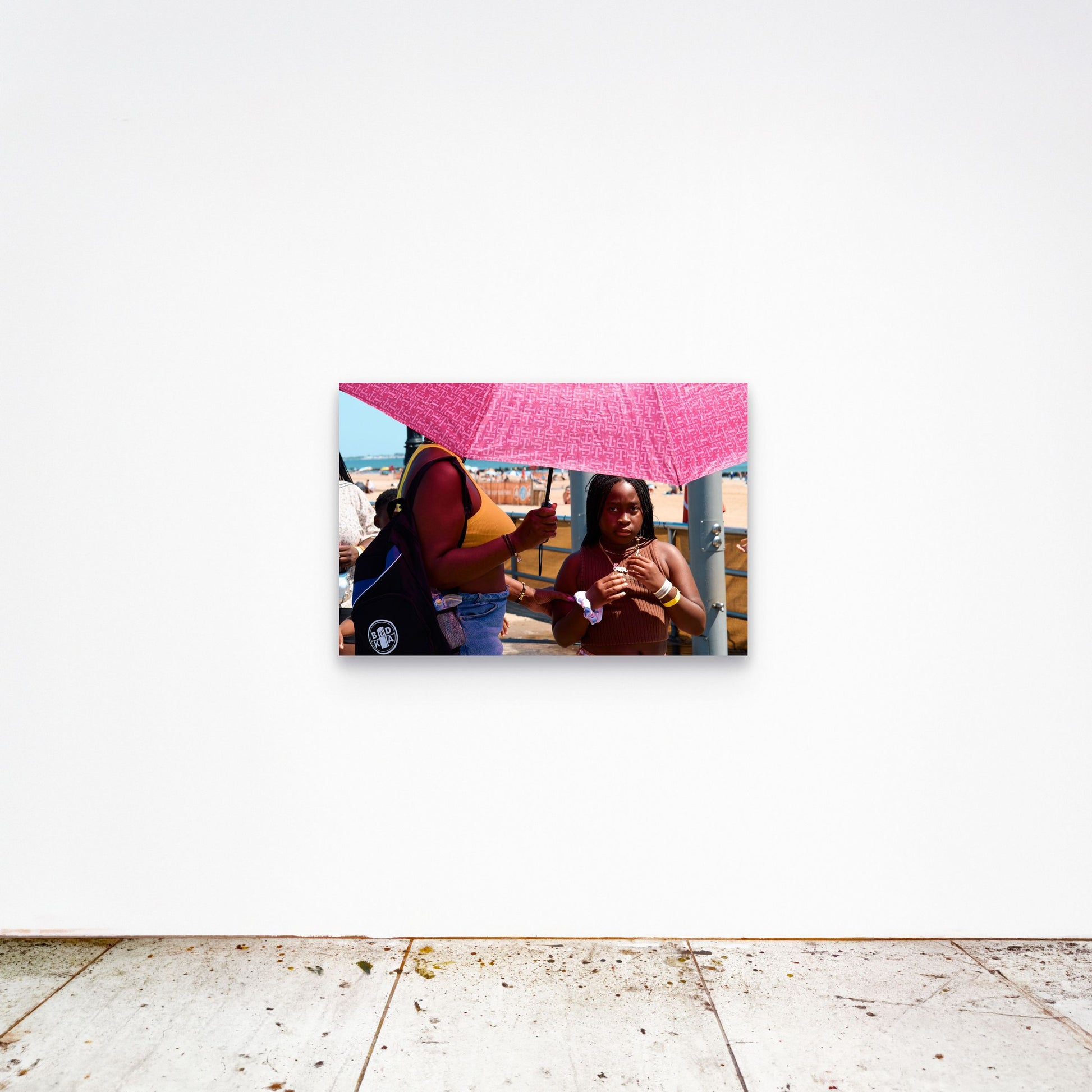 Chloe Albert's fine art print 'Pink Umbrella' shown unframed at 36 by 24 inches on a gallery wall, displaying the print at scale in a room setting.