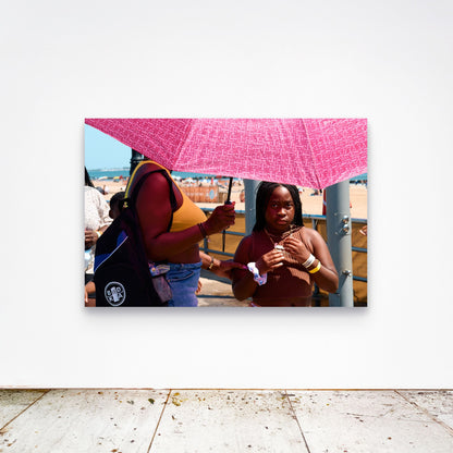 Chloe Albert's fine art print 'Pink Umbrella' shown unframed at 60 by 40 inches on a gallery wall above a concrete floor, displaying the large statement size in a room.
