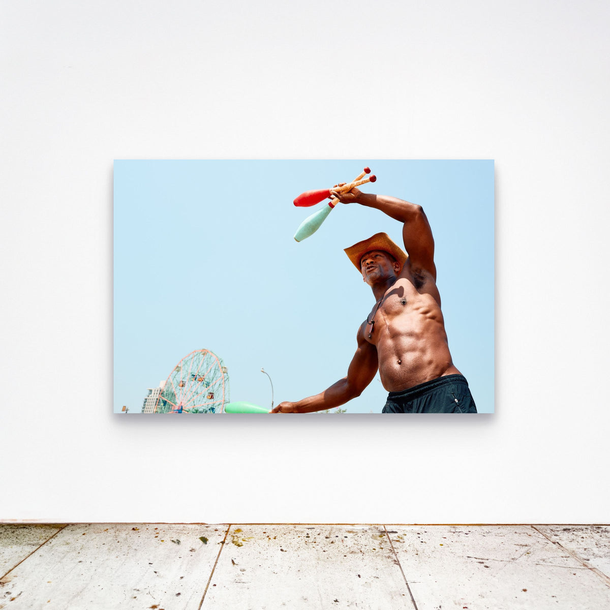Chloe Albert's fine art print 'The Juggler' shown unframed at 60 by 40 inches on a gallery wall above a concrete floor, displaying the large statement size in a room.