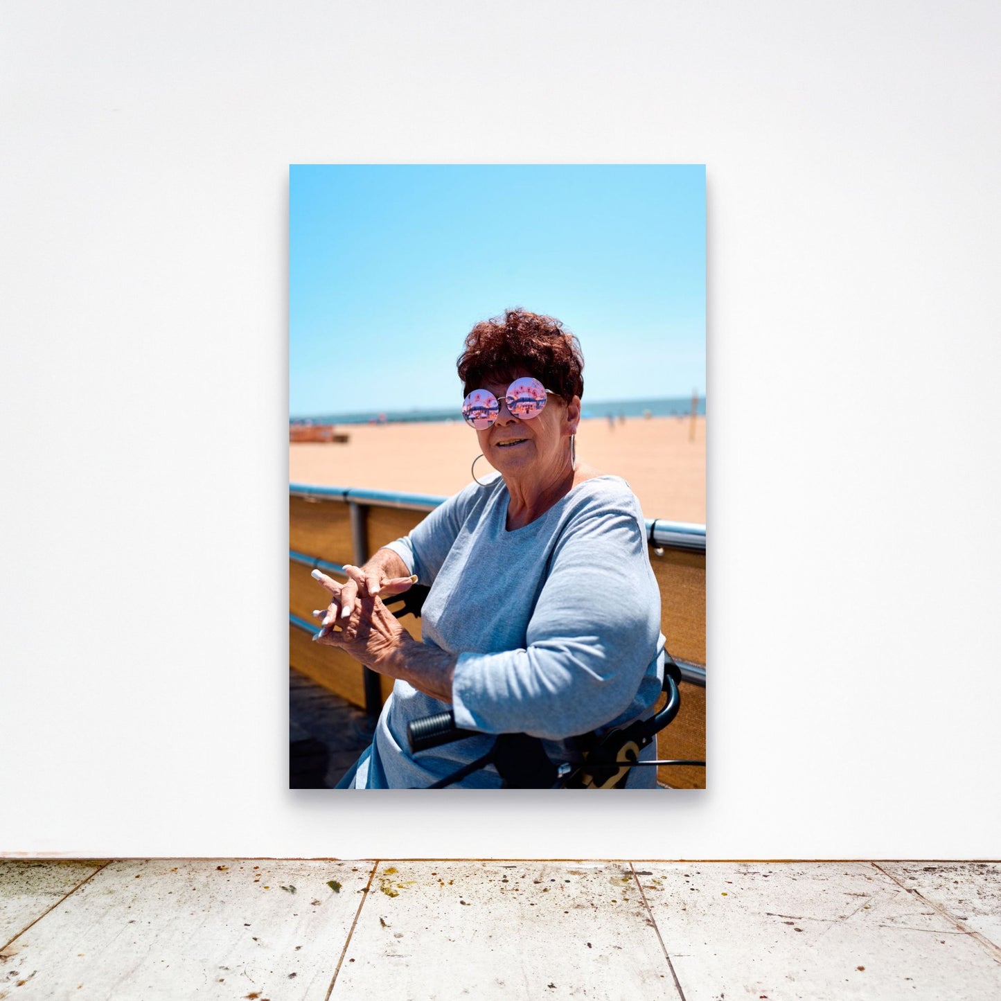 Chloe Albert's fine art print 'Woman On Broadwalk' shown unframed at 60 by 40 inches on a gallery wall above a concrete floor, displaying the large statement size in a room.