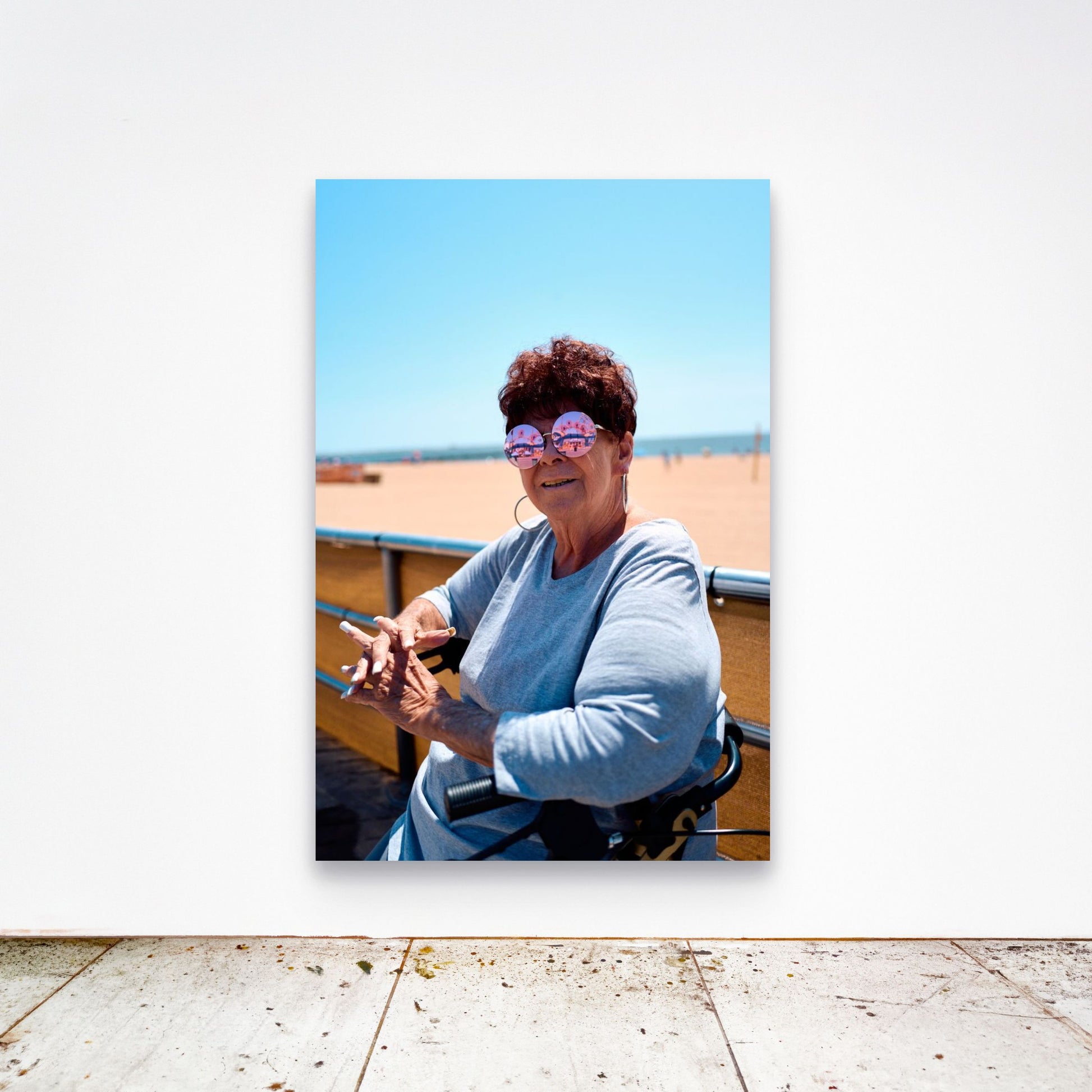 Chloe Albert's fine art print 'Woman On Broadwalk' shown unframed at 60 by 40 inches on a gallery wall above a concrete floor, displaying the large statement size in a room.
